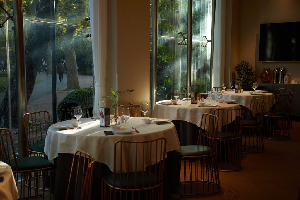 HOMES上海本帮菜餐厅环境 - 阳光透过落地窗洒在精致的圆桌上，展现优雅静谧的上海老洋房用餐氛围。